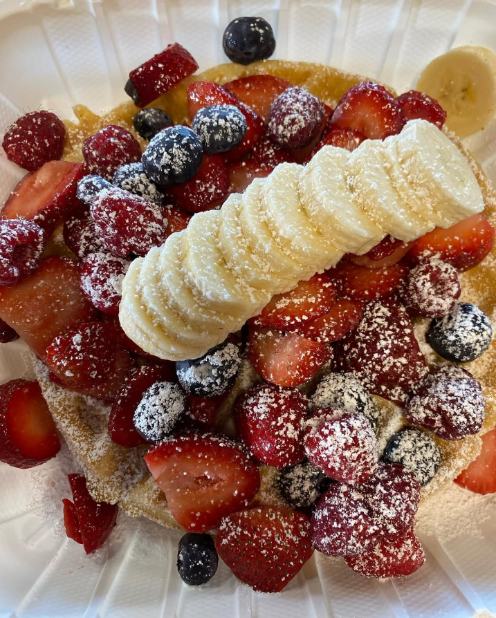 Fresh mixed-berry Belgian waffle dusted with powdered sugar