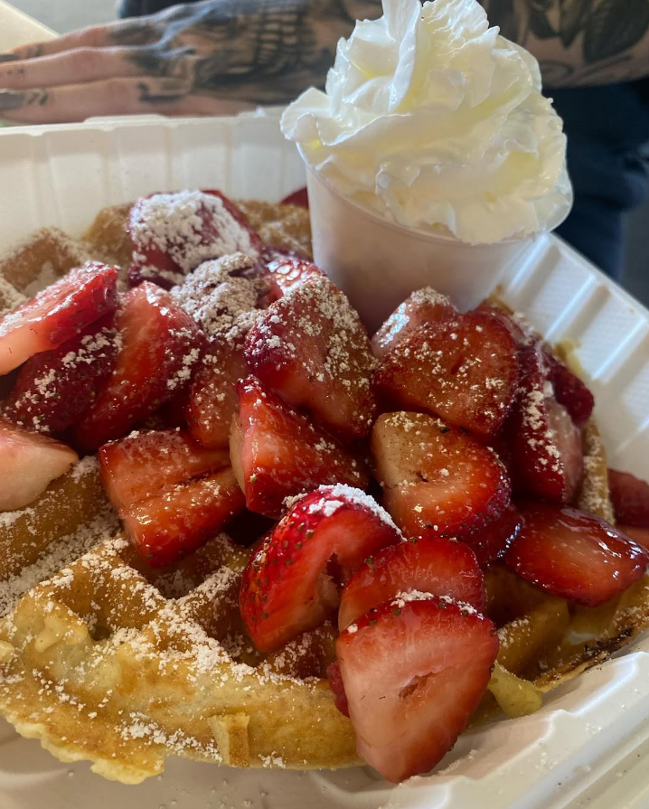 Belgian waffle piled with fresh strawberries and whipped cream